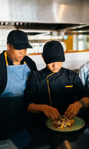 pexels-photo-6937480-6937480 Three chefs collaborate in a kitchen, focused on food preparation and culinary craft.