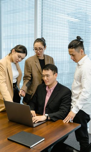 pexels-photo-7643859-7643859 A diverse team collaborates around a laptop in a modern office setting.
